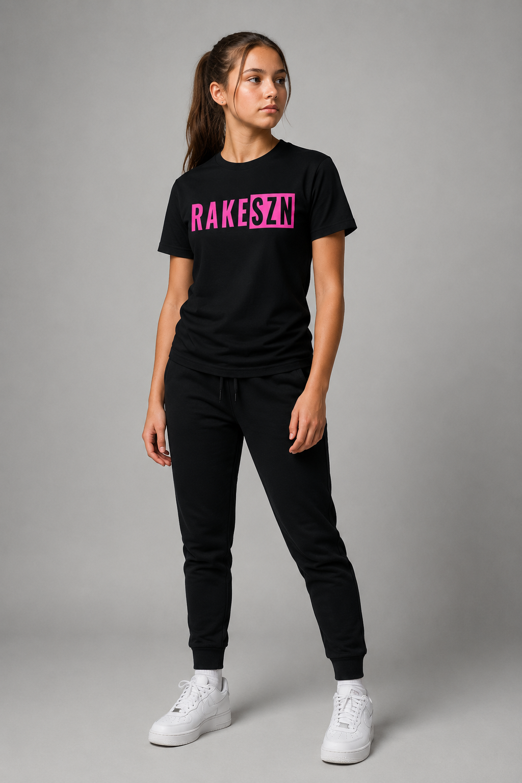 Model wearing the black RAKE SZN t-shirt with pink graphic by Rake City.