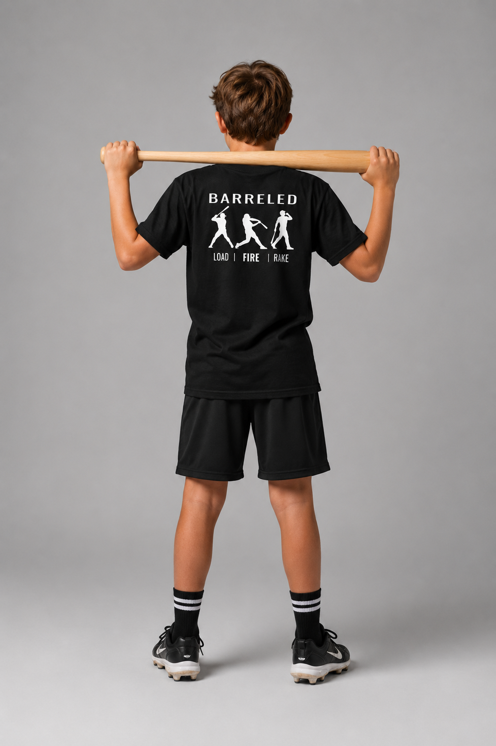 Model wearing the black youth BARRELED premium baseball t-shirt by Rake City.