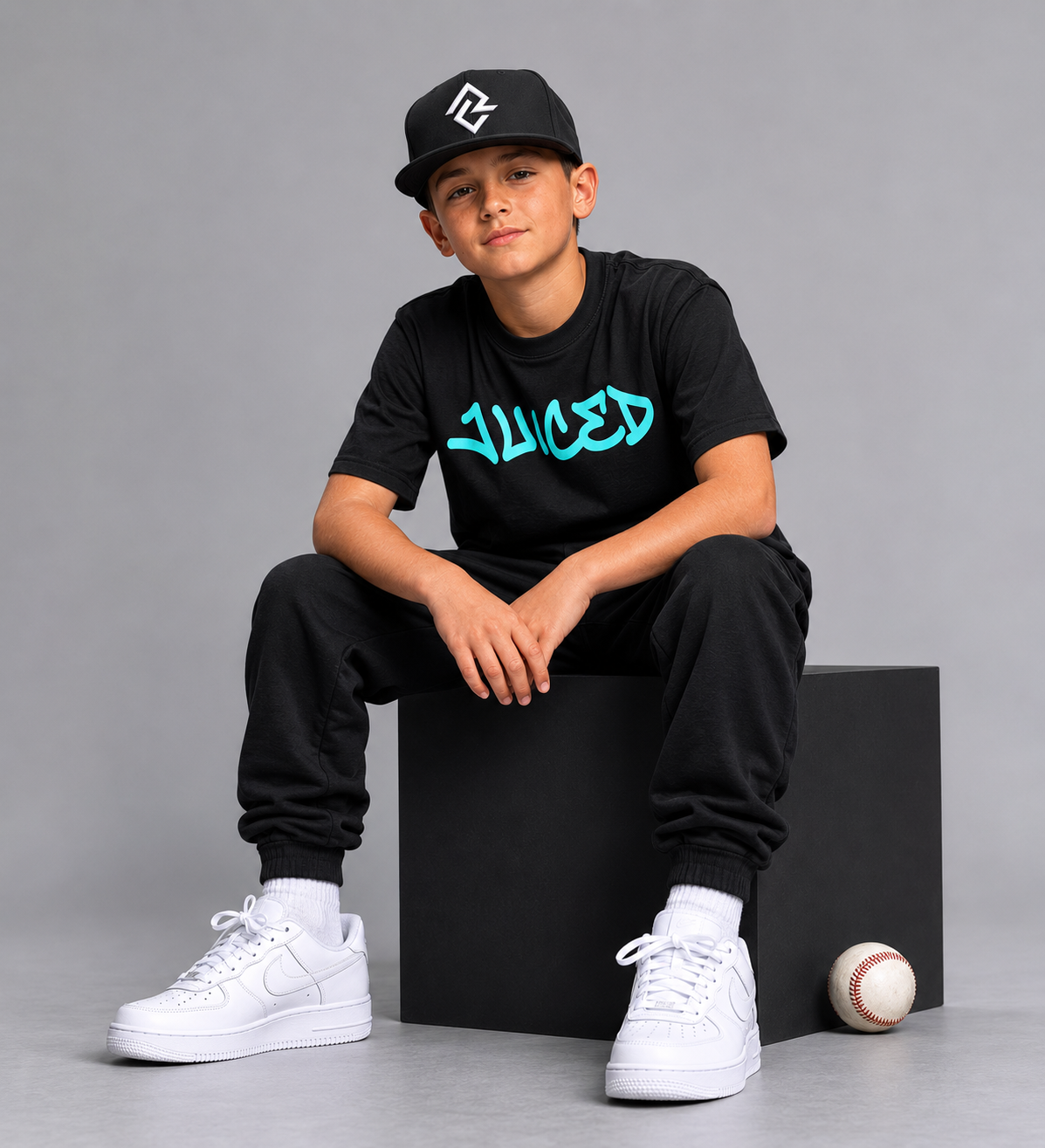 Model wearing the youth JUICED premium baseball t-shirt and RC logo snapback hat.